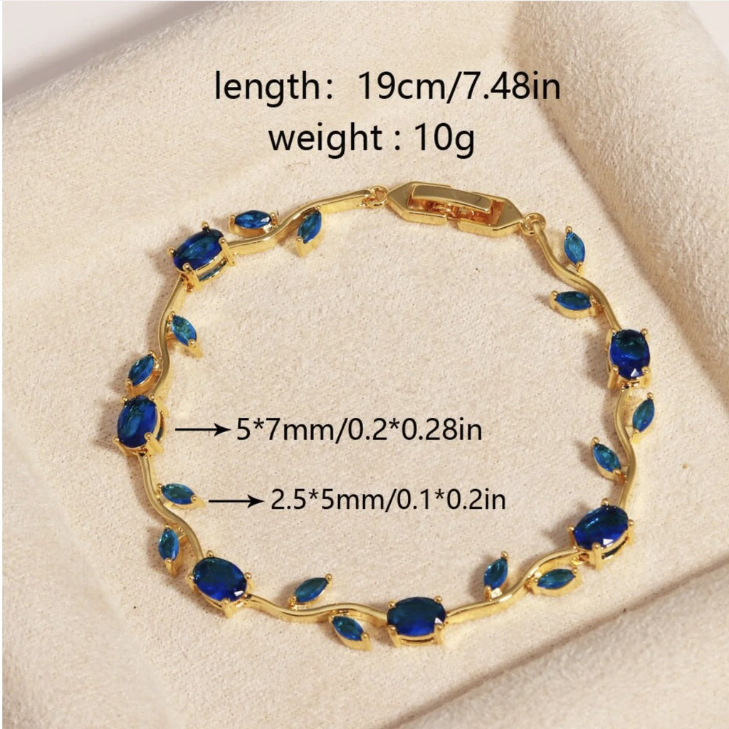 Gold bracelet with oval and marquise-cut blue gemstones, displayed on a cream textured surface with overlaid size and weight information. sasha jewels 