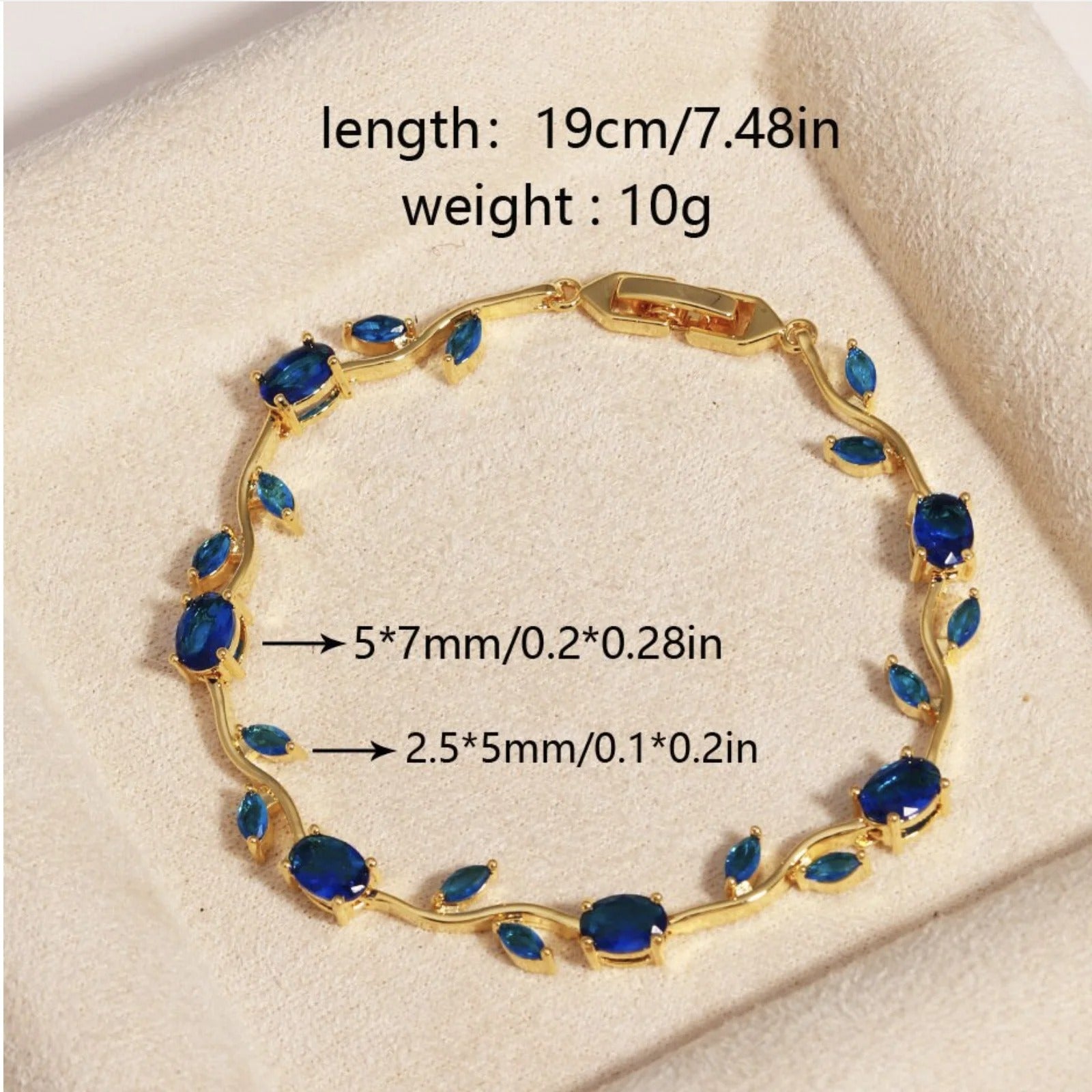 Gold bracelet with oval and marquise-cut blue gemstones, displayed on a cream textured surface with overlaid size and weight information. sasha jewels 